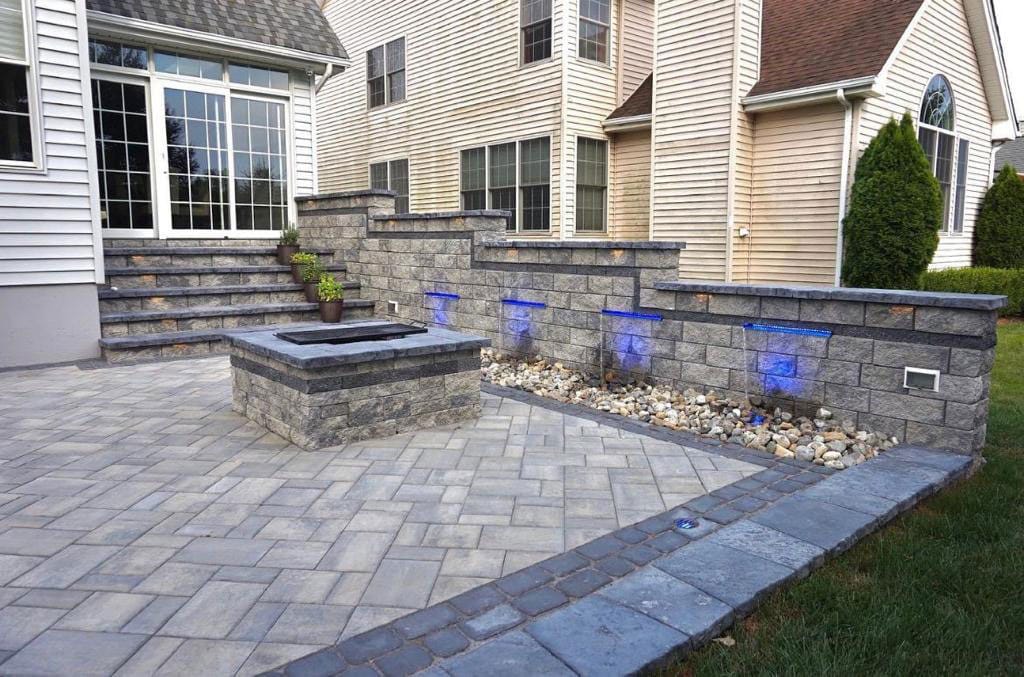 Paver patio with a fire pit and landscape lighting