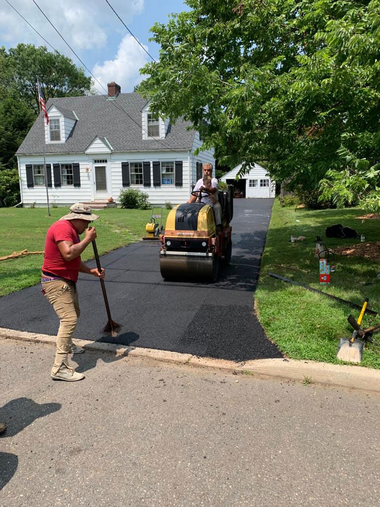 Crew raking hot asphalt behind the roller