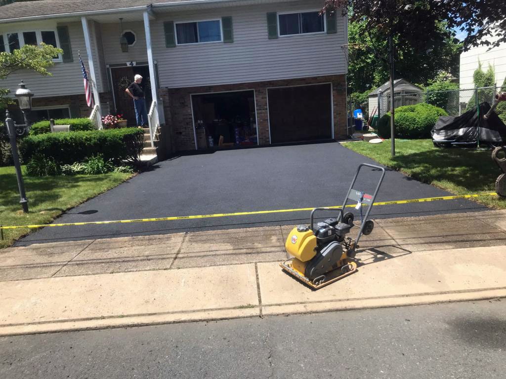 Plate compactor finishing a resurfaced driveway