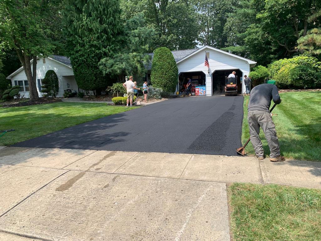 Roller compacting a repaired asphalt driveway